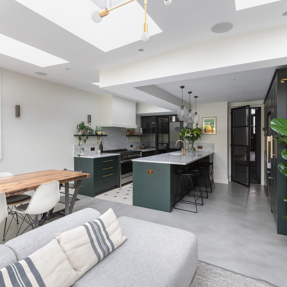 Example of a mid-sized trendy u-shaped concrete floor and gray floor eat-in kitchen design in London with an integrated sink, shaker cabinets, green cabinets, marble countertops, white backsplash, marble backsplash, stainless steel appliances, an island and white countertops