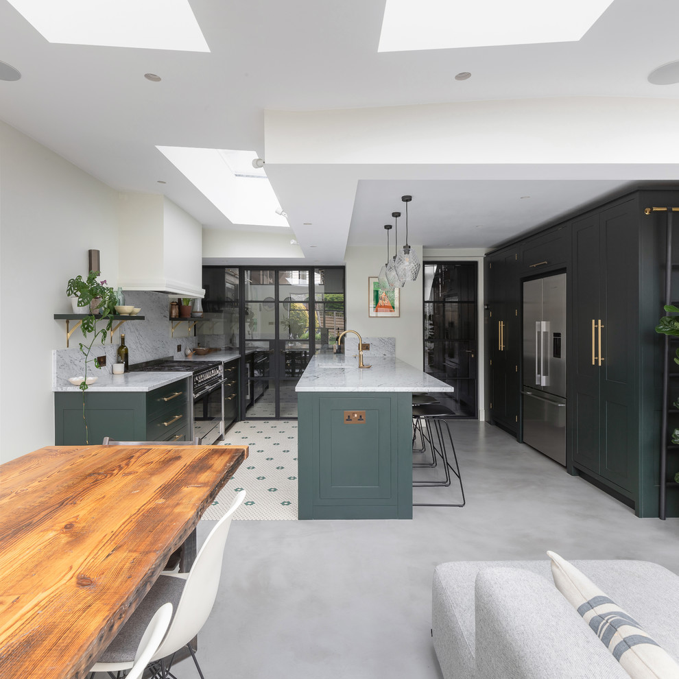 Photo of a medium sized contemporary u-shaped kitchen/diner in London with an integrated sink, shaker cabinets, green cabinets, marble worktops, white splashback, marble splashback, stainless steel appliances, concrete flooring, an island, grey floors and white worktops.