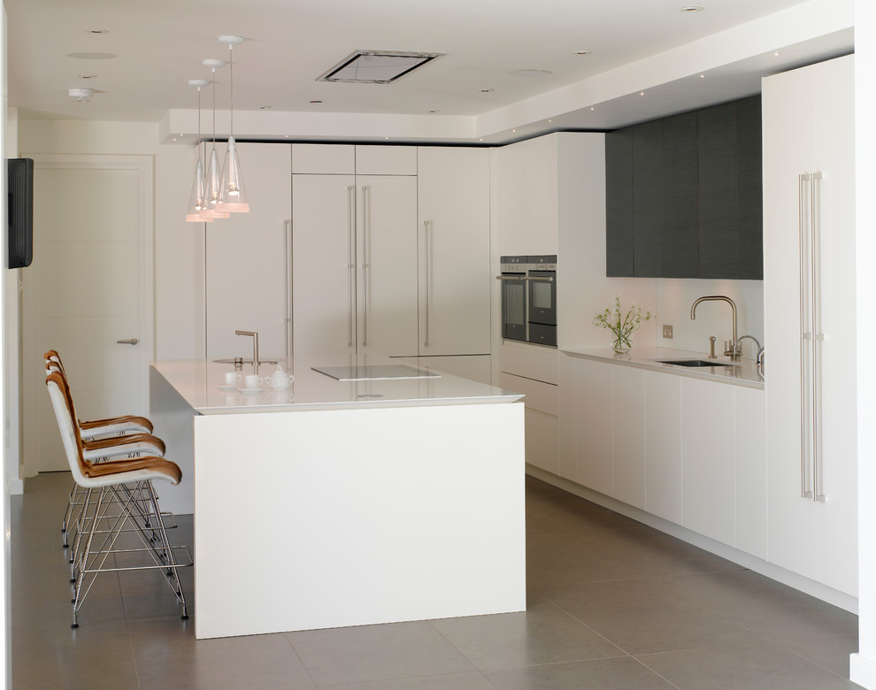 Photo of a large contemporary l-shaped kitchen/diner in London with flat-panel cabinets, white cabinets, quartz worktops, white splashback, glass sheet splashback, integrated appliances, ceramic flooring, an island, grey floors, white worktops and a submerged sink.