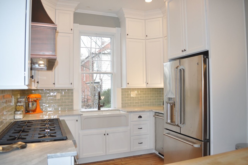 Example of a mid-sized cottage u-shaped light wood floor enclosed kitchen design in Richmond with a farmhouse sink, flat-panel cabinets, white cabinets, marble countertops, green backsplash, terra-cotta backsplash and stainless steel appliances