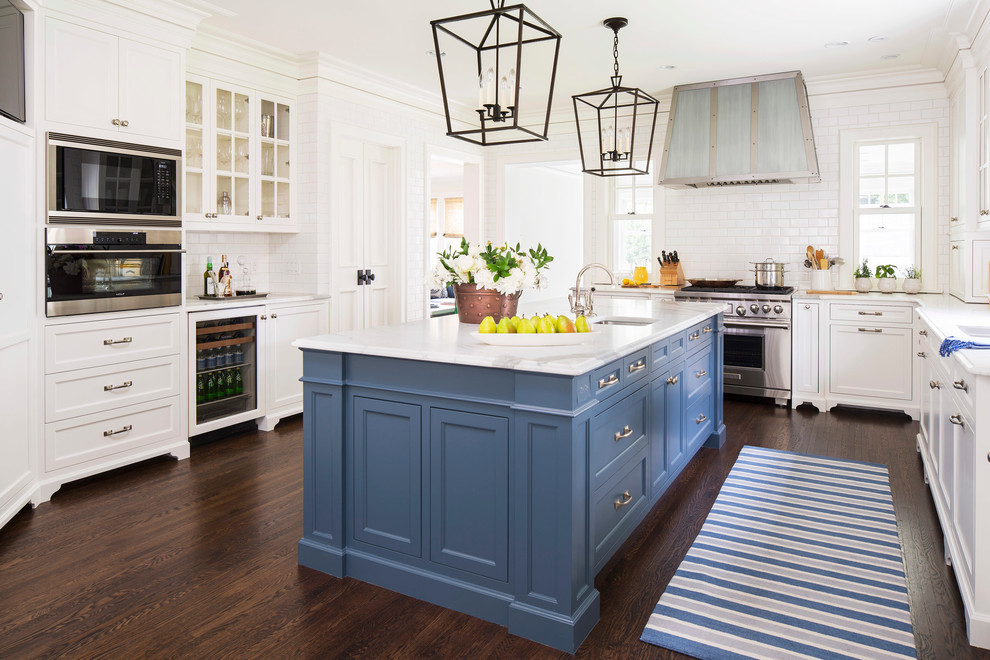 Example of a classic l-shaped dark wood floor kitchen design in Minneapolis with an undermount sink, shaker cabinets, white cabinets, marble countertops, white backsplash, subway tile backsplash, stainless steel appliances and an island