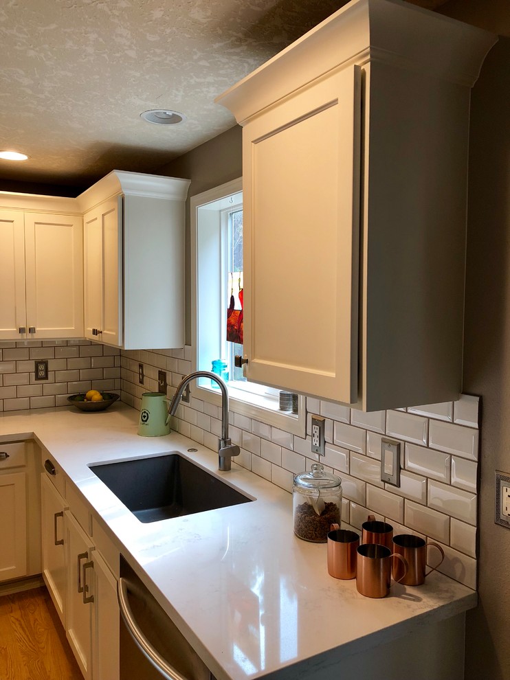 Example of a small classic u-shaped light wood floor and yellow floor enclosed kitchen design in Portland with an undermount sink, recessed-panel cabinets, white cabinets, quartz countertops, subway tile backsplash, stainless steel appliances, no island and white countertops