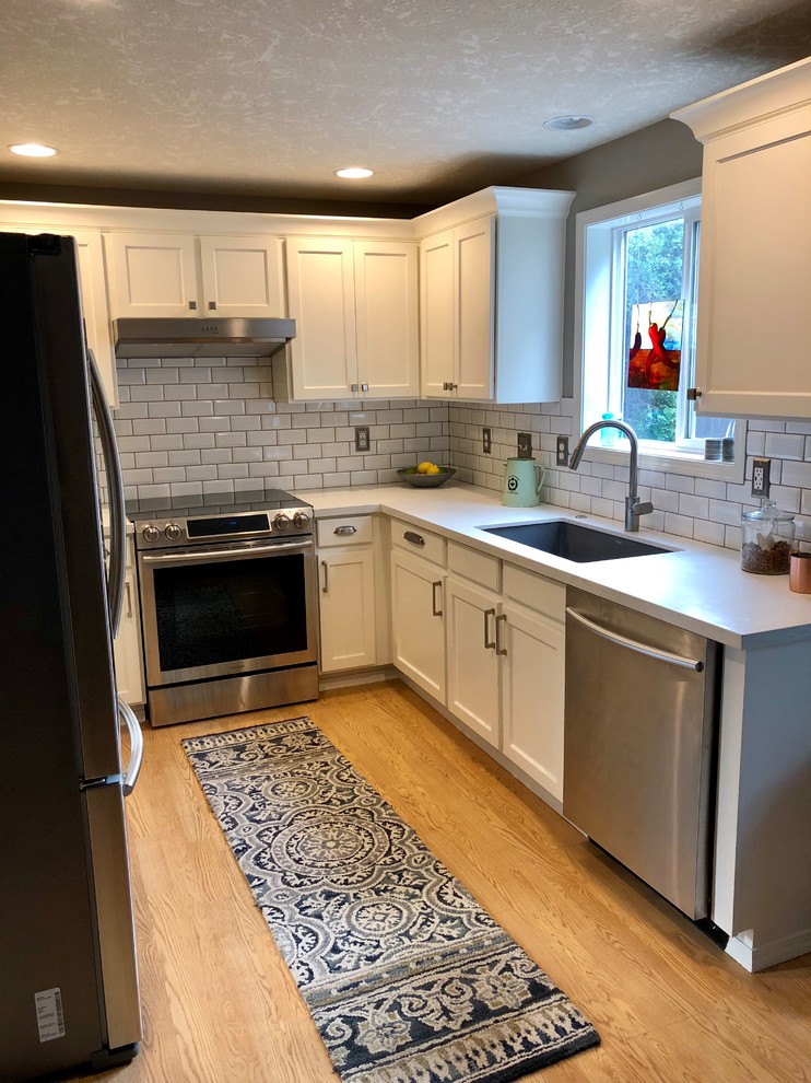 Inspiration for a small classic u-shaped enclosed kitchen in Portland with a submerged sink, recessed-panel cabinets, white cabinets, engineered stone countertops, metro tiled splashback, stainless steel appliances, light hardwood flooring, no island, yellow floors and white worktops.