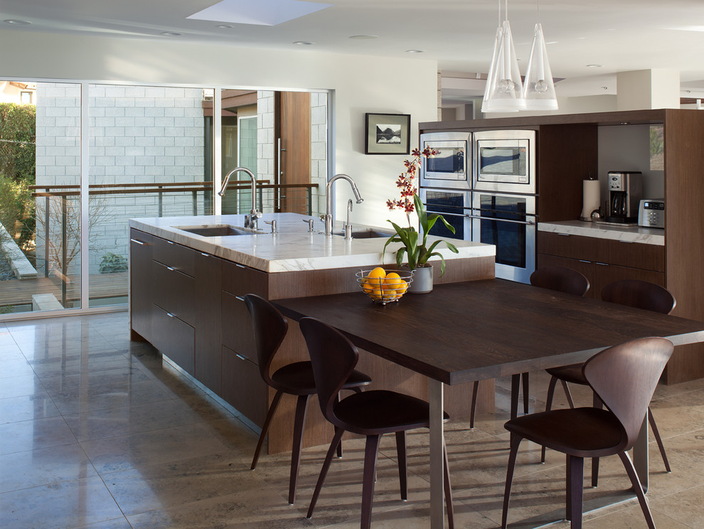 Moderne Wohnküche mit flächenbündigen Schrankfronten, dunklen Holzschränken, Küchengeräten aus Edelstahl, Kücheninsel und Unterbauwaschbecken in San Diego