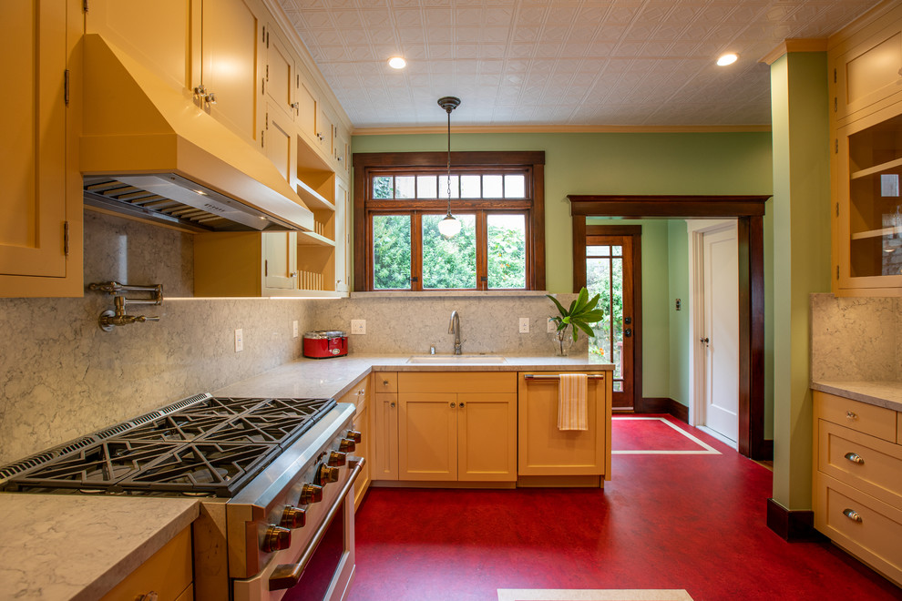 Example of a mid-sized arts and crafts u-shaped linoleum floor and red floor kitchen pantry design in San Francisco with an undermount sink, shaker cabinets, yellow cabinets, quartz countertops, gray backsplash, marble backsplash, paneled appliances, an island and gray countertops