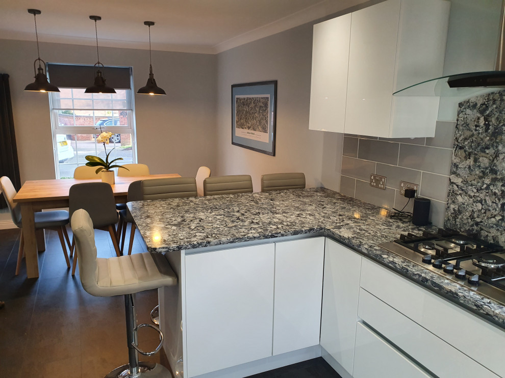 Medium sized contemporary u-shaped kitchen/diner in West Midlands with a double-bowl sink, flat-panel cabinets, white cabinets, quartz worktops, multi-coloured splashback, black appliances, ceramic flooring, no island, black floors and multicoloured worktops.