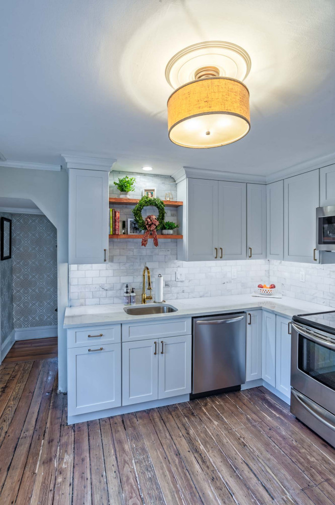Bild på ett avskilt, litet lantligt vit vitt l-kök, med en undermonterad diskho, skåp i shakerstil, gula skåp, bänkskiva i kvarts, vitt stänkskydd, stänkskydd i stenkakel, mellanmörkt trägolv och brunt golv