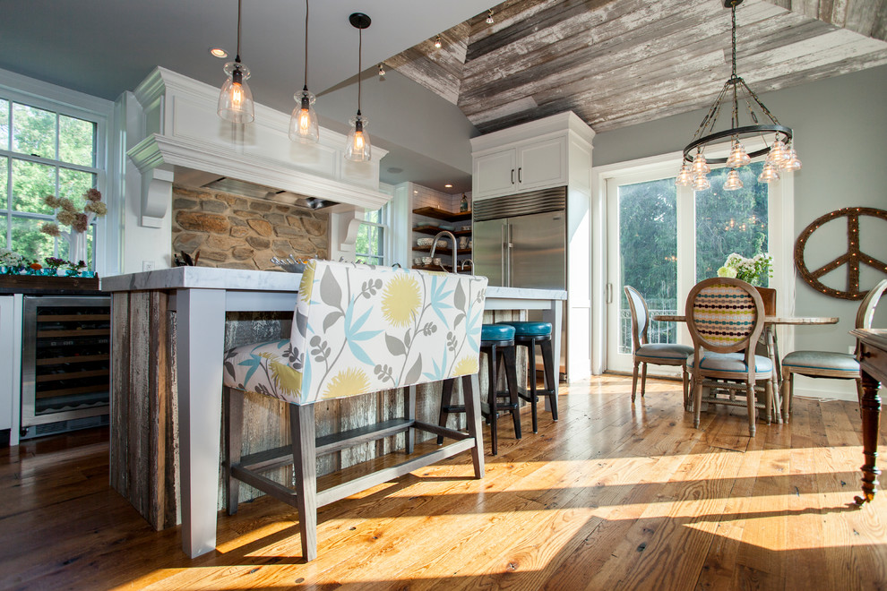 Mid-sized country l-shaped medium tone wood floor eat-in kitchen photo in Philadelphia with a farmhouse sink, shaker cabinets, white cabinets, marble countertops, white backsplash, subway tile backsplash, stainless steel appliances and an island