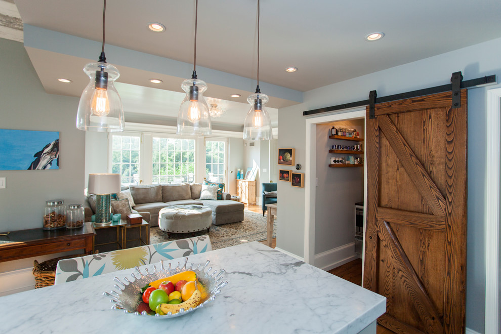Example of a mid-sized cottage l-shaped medium tone wood floor eat-in kitchen design in Philadelphia with a farmhouse sink, shaker cabinets, white cabinets, marble countertops, white backsplash, subway tile backsplash, stainless steel appliances and an island