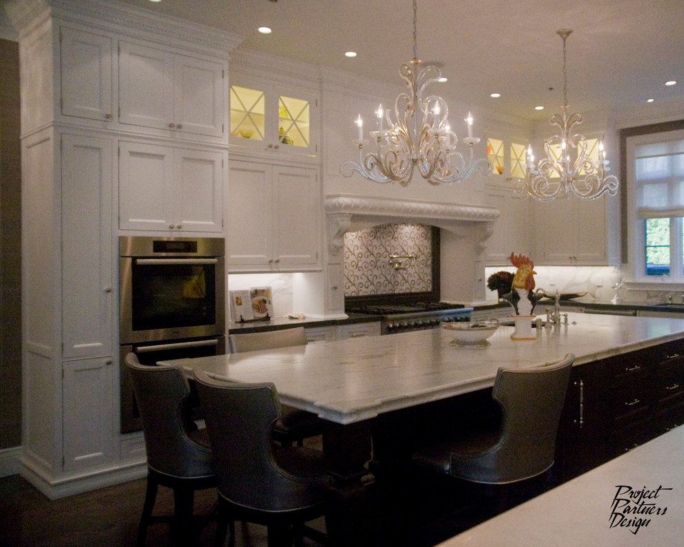 Inredning av ett klassiskt kök, med en undermonterad diskho, luckor med profilerade fronter, vita skåp, marmorbänkskiva, vitt stänkskydd och rostfria vitvaror