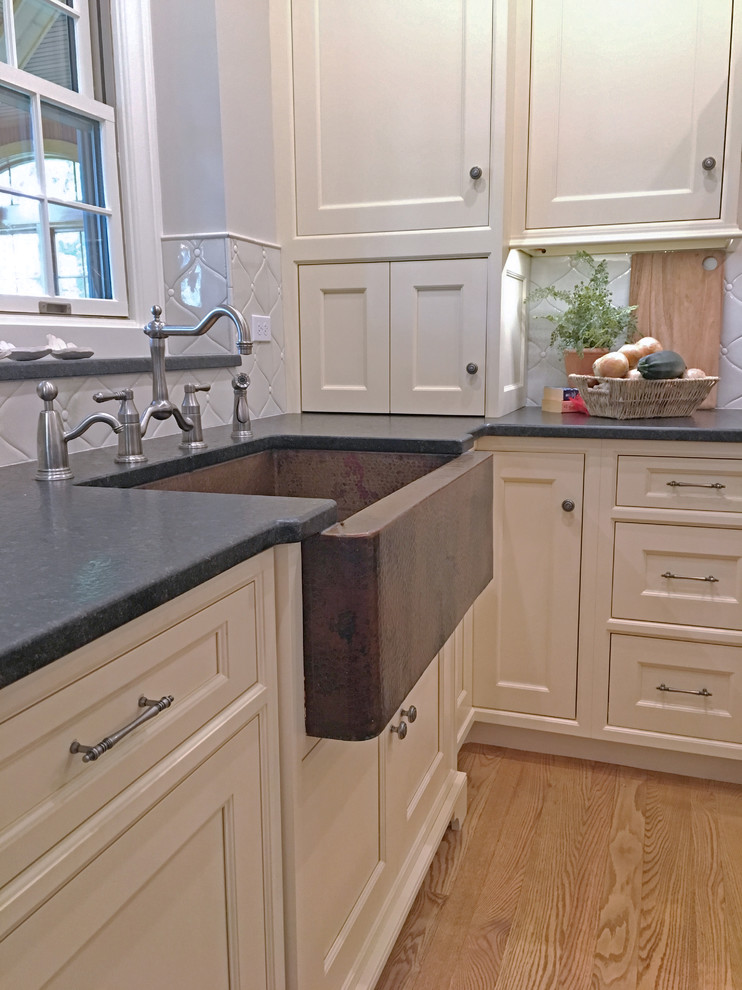 Bild på ett mellanstort lantligt kök, med en rustik diskho, luckor med upphöjd panel, vita skåp, bänkskiva i kvartsit, vitt stänkskydd, stänkskydd i keramik, integrerade vitvaror, ljust trägolv och en köksö