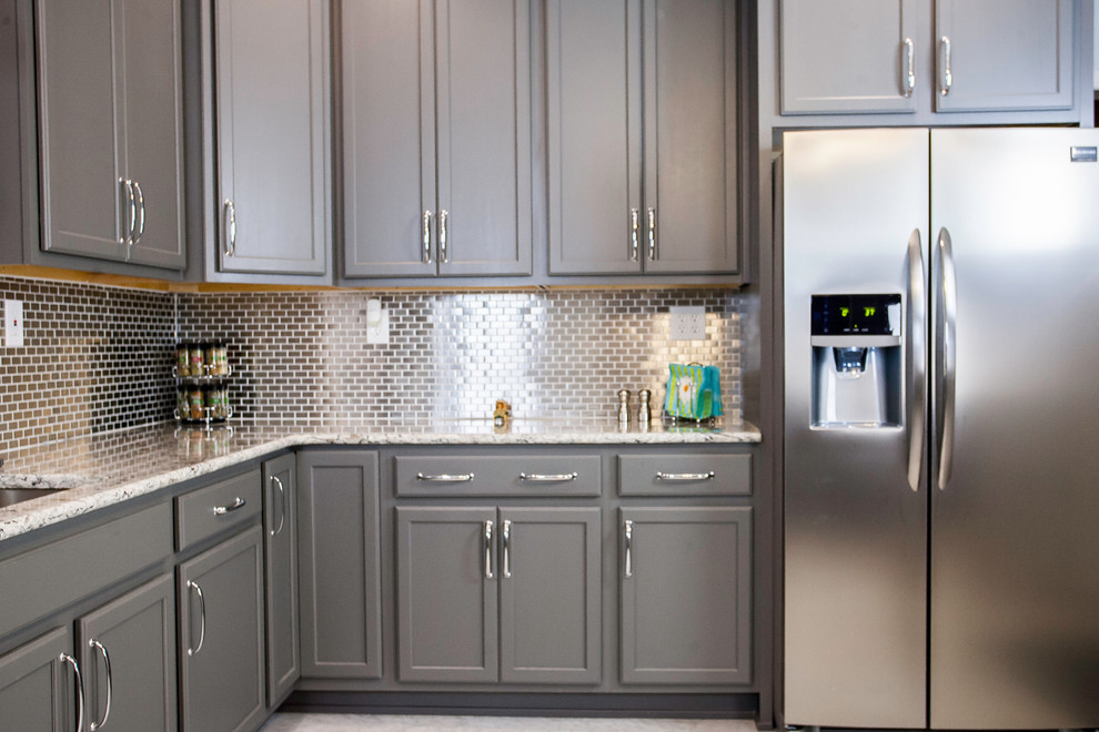 Exempel på ett mellanstort klassiskt kök, med en undermonterad diskho, luckor med upphöjd panel, grå skåp, granitbänkskiva, stänkskydd med metallisk yta, stänkskydd i metallkakel, rostfria vitvaror, klinkergolv i keramik, en köksö och beiget golv