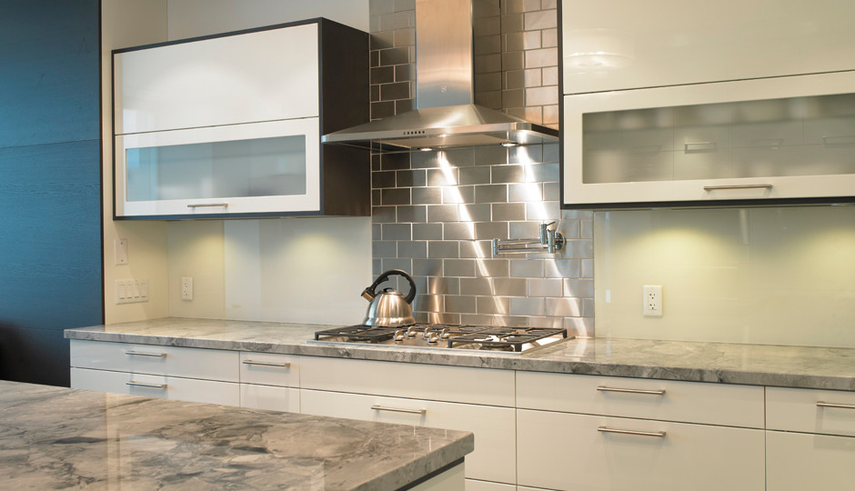 Glass and metal back splash detail in kitchen, contrasting uppers