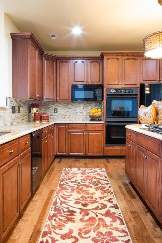 Foto på ett mellanstort vintage kök, med en undermonterad diskho, luckor med upphöjd panel, skåp i mellenmörkt trä, granitbänkskiva, flerfärgad stänkskydd, svarta vitvaror, mellanmörkt trägolv, en köksö och stänkskydd i mosaik