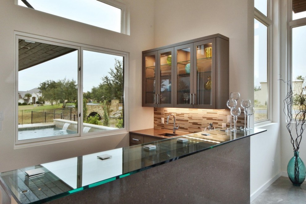 Réalisation d'une cuisine design avec un placard à porte vitrée et un plan de travail en verre.