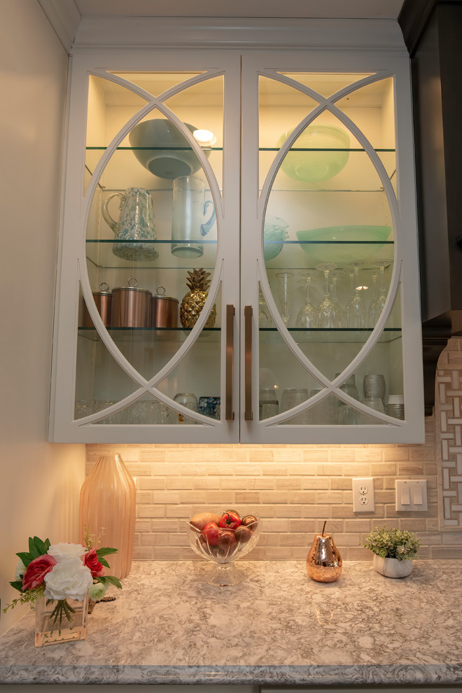 Idée de décoration pour une cuisine américaine linéaire avec un placard à porte vitrée, des portes de placard blanches, un sol en vinyl, îlot et un sol marron.