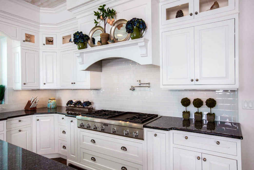 Exempel på ett klassiskt kök, med luckor med upphöjd panel, vita skåp, granitbänkskiva, vitt stänkskydd, stänkskydd i tunnelbanekakel, rostfria vitvaror, mörkt trägolv och en köksö