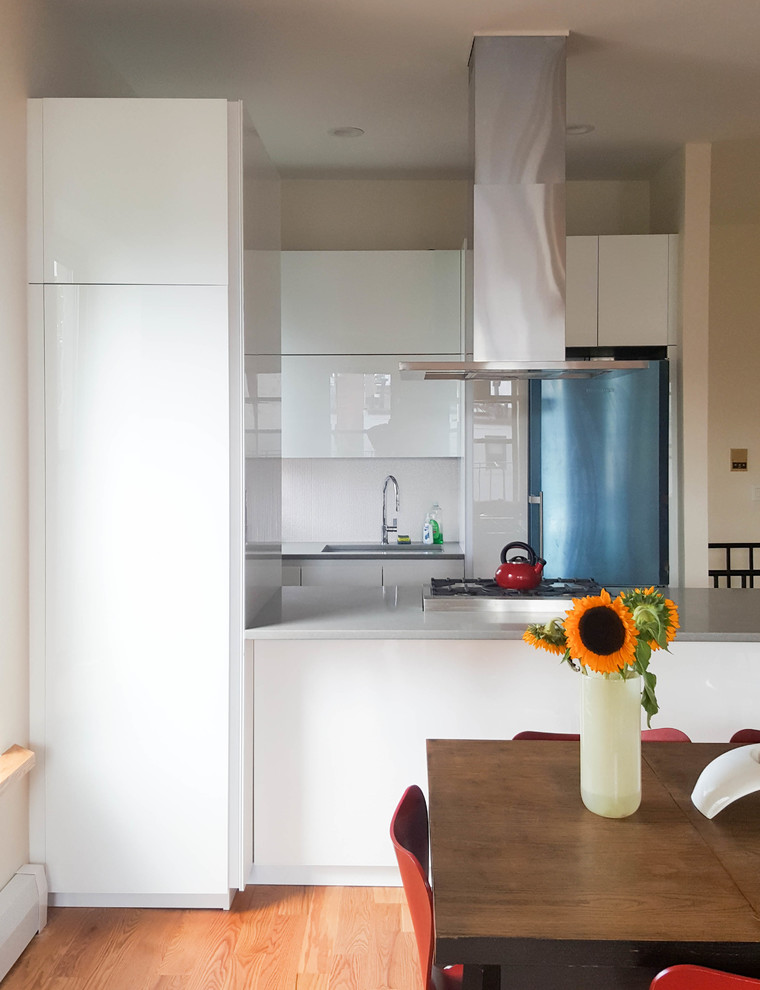 Foto på ett mellanstort funkis kök, med en undermonterad diskho, luckor med glaspanel, vita skåp, bänkskiva i kvarts, vitt stänkskydd, stänkskydd i porslinskakel, vita vitvaror, mellanmörkt trägolv, en köksö och gult golv