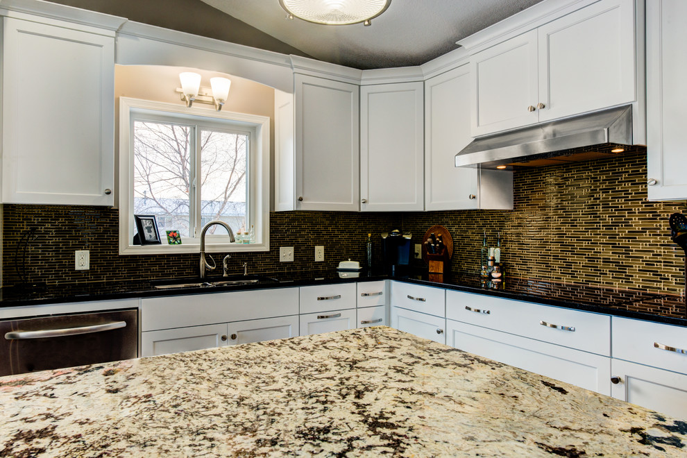 Exempel på ett mellanstort klassiskt l-kök, med en dubbel diskho, skåp i shakerstil, vita skåp, granitbänkskiva, brunt stänkskydd, stänkskydd i stickkakel, rostfria vitvaror, klinkergolv i porslin, en köksö och beiget golv