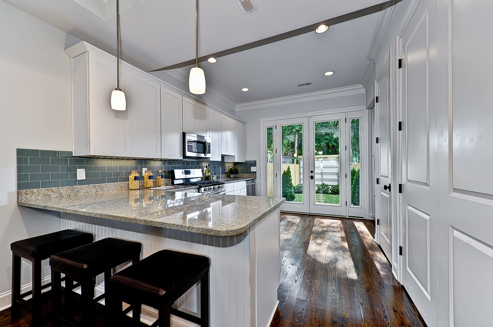 Diseño de cocina tradicional con puertas de armario blancas, salpicadero verde, salpicadero de azulejos de vidrio y electrodomésticos de acero inoxidable