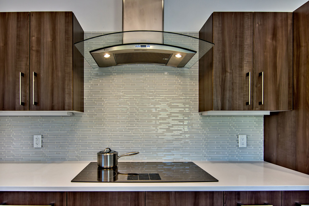 Immagine di una cucina moderna con lavello sottopiano, ante lisce, ante in legno scuro, top in quarzite, paraspruzzi grigio e elettrodomestici in acciaio inossidabile