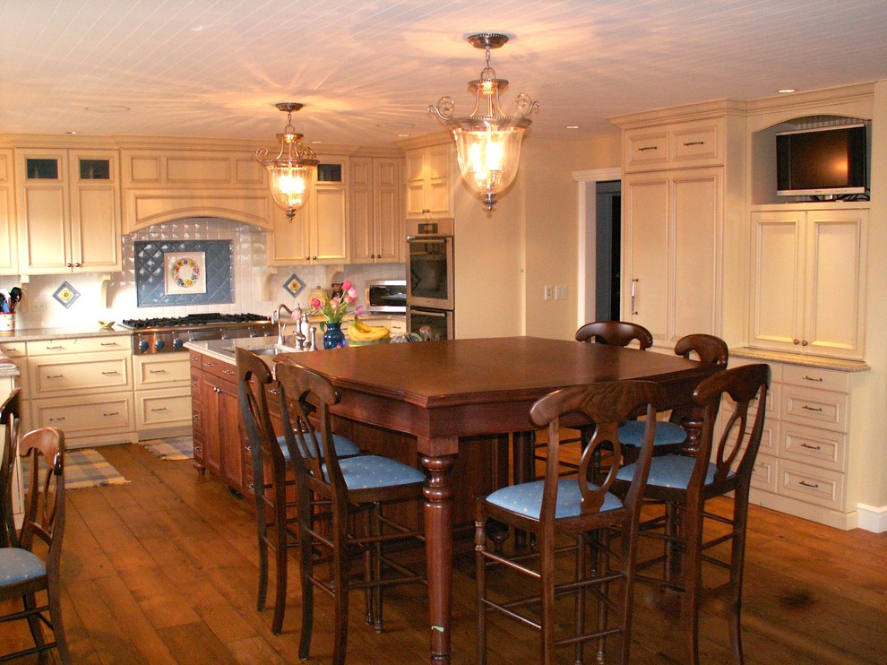 Foto på ett vintage kök, med luckor med infälld panel, skåp i slitet trä, granitbänkskiva, vitt stänkskydd, stänkskydd i keramik, integrerade vitvaror, mellanmörkt trägolv och en köksö