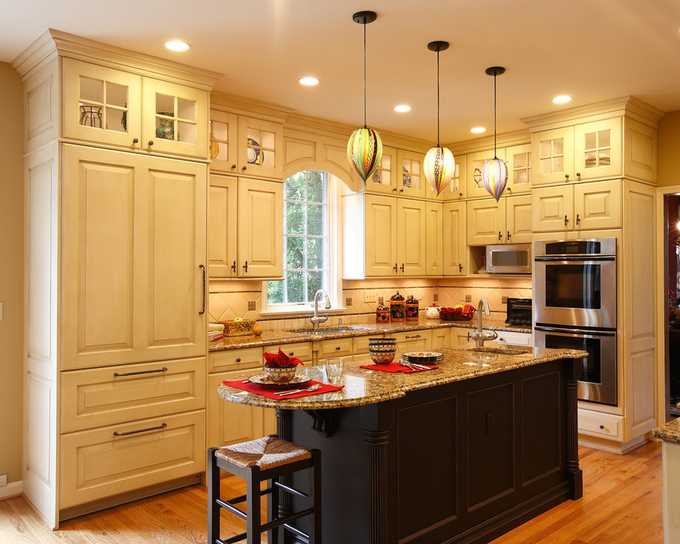 Exempel på ett stort klassiskt kök, med en enkel diskho, luckor med upphöjd panel, beige skåp, granitbänkskiva, beige stänkskydd, stänkskydd i keramik, rostfria vitvaror, mellanmörkt trägolv, en köksö och brunt golv