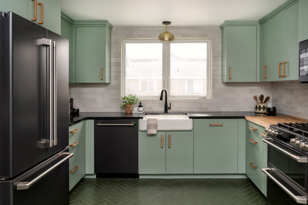 ボイシにあるお手頃価格の広いトランジショナルスタイルのおしゃれなキッチン (緑のキャビネット、白いキッチンパネル、レンガのキッチンパネル、レンガの床、緑の床、黒いキッチンカウンター) の写真