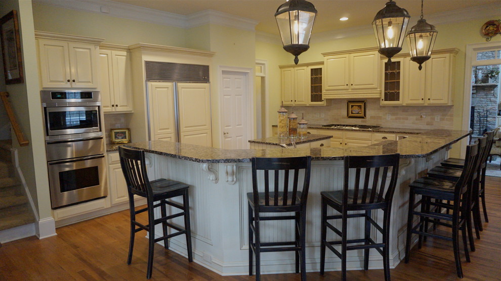 This is an example of a large classic u-shaped kitchen/diner in Atlanta with a submerged sink, distressed cabinets, granite worktops, beige splashback, metro tiled splashback, stainless steel appliances and medium hardwood flooring.