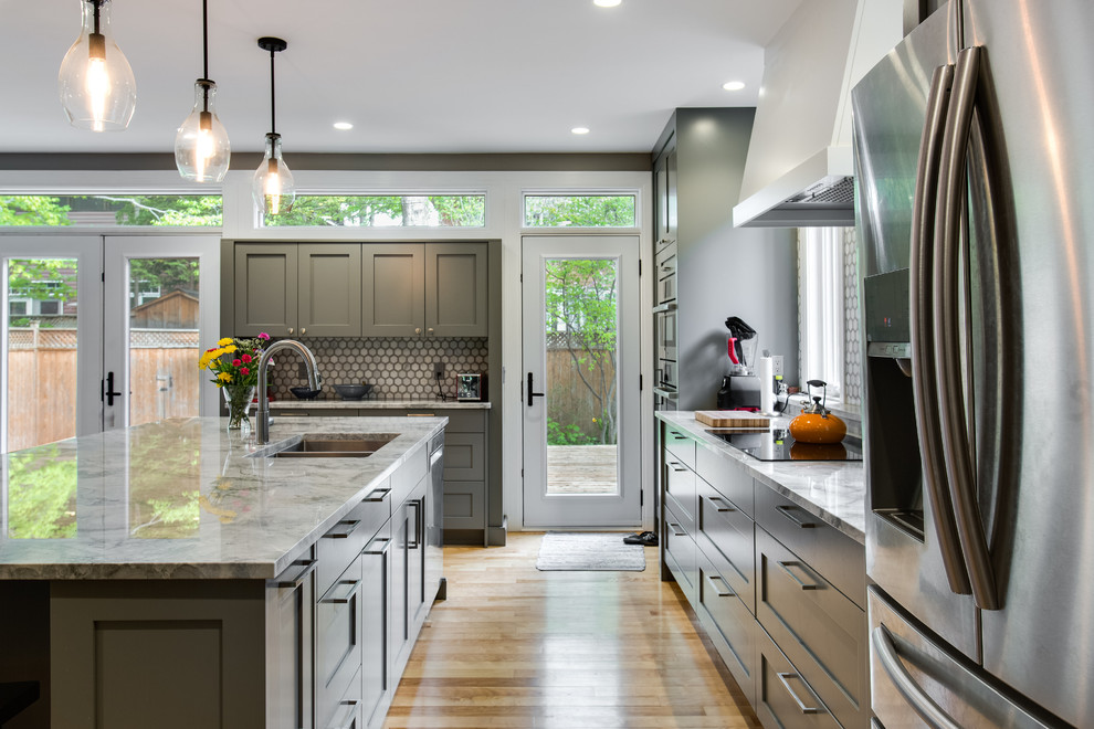 This is an example of a large modern l-shaped kitchen/diner in Ottawa with a submerged sink, recessed-panel cabinets, grey cabinets, marble worktops, grey splashback, stone tiled splashback, stainless steel appliances, light hardwood flooring and an island.