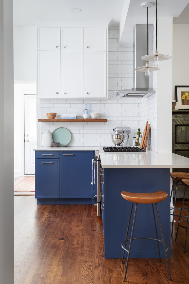 Mittelgroße Klassische Küche mit Schrankfronten im Shaker-Stil, Küchenrückwand in Weiß, Rückwand aus Metrofliesen, Küchengeräten aus Edelstahl, Halbinsel, weißer Arbeitsplatte, blauen Schränken, dunklem Holzboden und braunem Boden in Ottawa