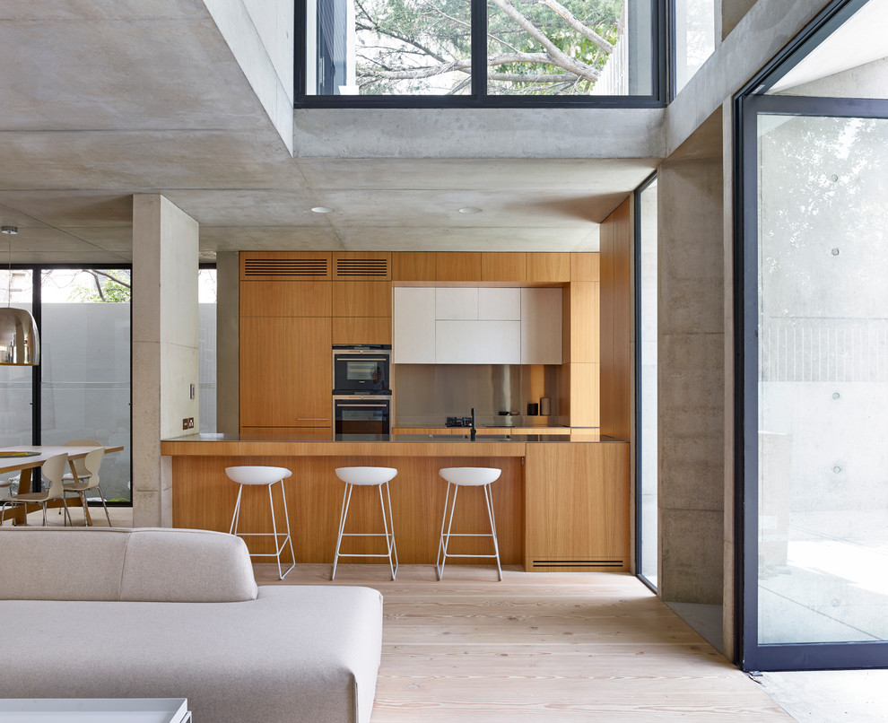 Exemple d'une cuisine ouverte parallèle tendance en bois brun avec un placard à porte plane et un sol en contreplaqué.