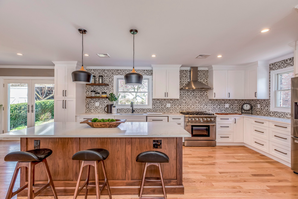 Photo of a medium sized contemporary kitchen/diner in New York with a submerged sink, shaker cabinets, white cabinets, composite countertops, cement tile splashback, stainless steel appliances, medium hardwood flooring, an island, beige floors and white worktops.