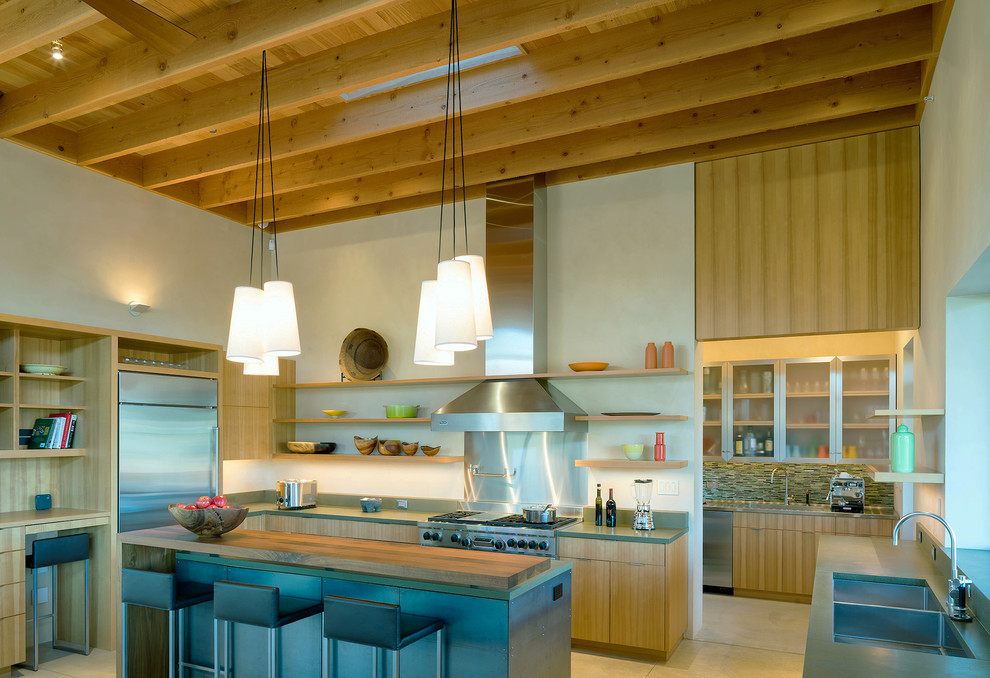 Aménagement d'une arrière-cuisine moderne en bois brun avec un placard à porte plane, un plan de travail en béton, un électroménager en acier inoxydable, sol en béton ciré et îlot.