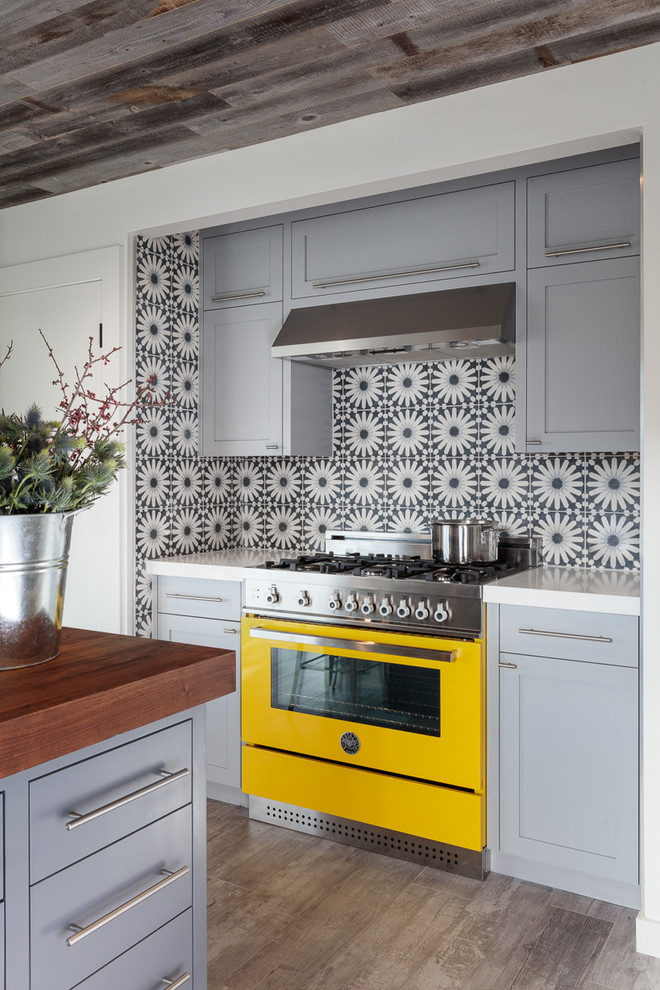 Example of an eclectic u-shaped light wood floor kitchen design in San Francisco with a farmhouse sink, shaker cabinets, blue cabinets, multicolored backsplash, ceramic backsplash, colored appliances and an island