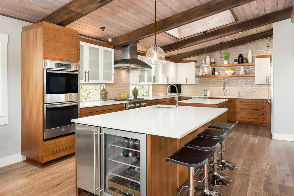 Kitchen - large 1950s l-shaped brown floor and light wood floor kitchen idea in Portland with solid surface countertops, beige backsplash, stainless steel appliances, two islands, flat-panel cabinets, an undermount sink and light wood cabinets