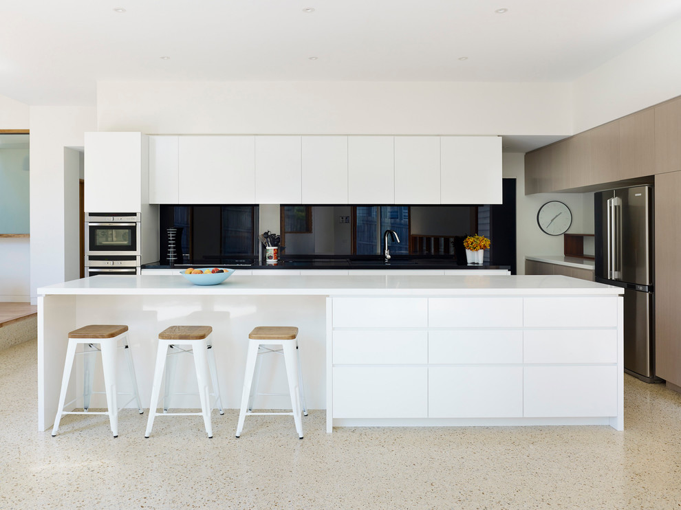 Modern inredning av ett stort kök, med svart stänkskydd, glaspanel som stänkskydd, en köksö, släta luckor, vita skåp, bänkskiva i kvarts, en dubbel diskho och rostfria vitvaror