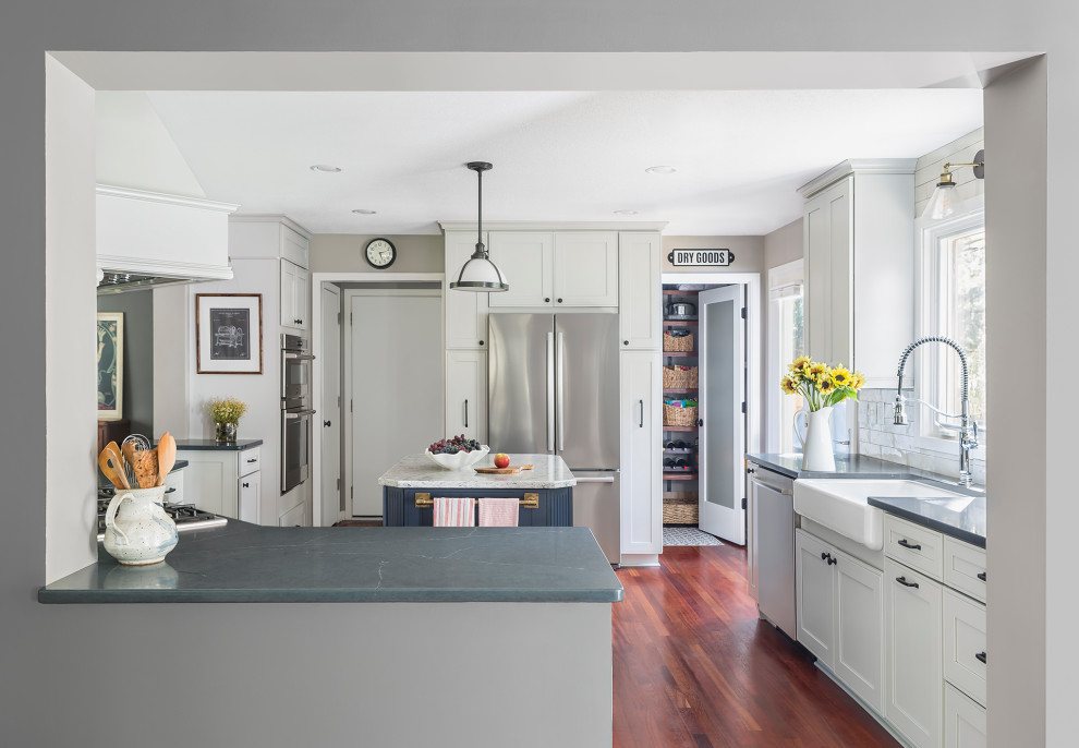 Bild på ett avskilt, mellanstort vintage grå grått u-kök, med en rustik diskho, luckor med infälld panel, vita skåp, bänkskiva i kvarts, vitt stänkskydd, stänkskydd i keramik, rostfria vitvaror, mellanmörkt trägolv, en köksö och rött golv