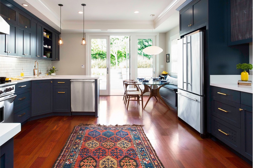 Inspiration for a large transitional u-shaped medium tone wood floor eat-in kitchen remodel in San Francisco with shaker cabinets, blue cabinets, white backsplash, ceramic backsplash, stainless steel appliances, a peninsula, a double-bowl sink and quartz countertops