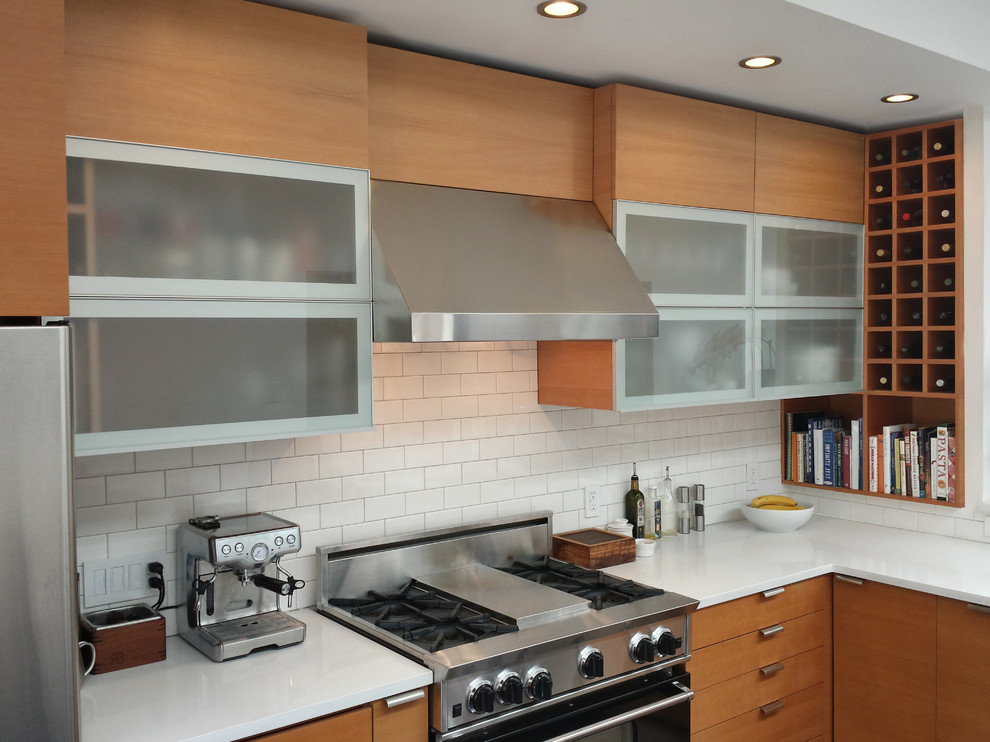 Cette image montre une cuisine design en bois clair avec une crédence en carrelage métro, un placard à porte plane, une crédence blanche et un électroménager en acier inoxydable.