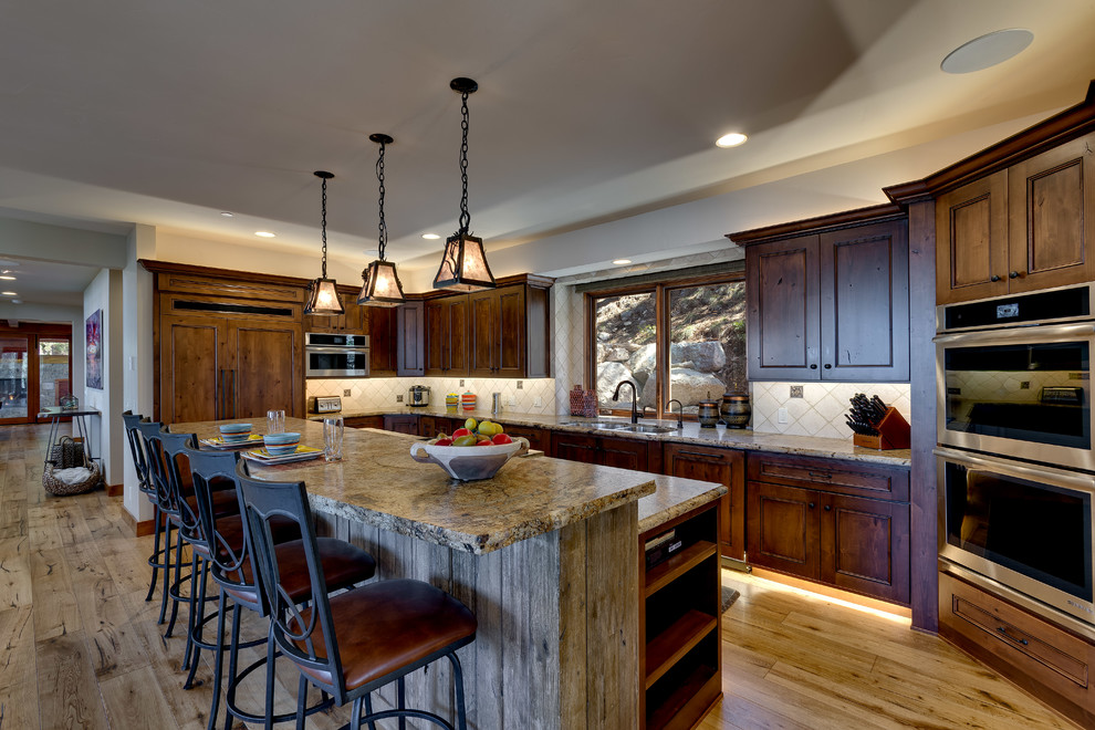 Inspiration for a large rustic l-shaped light wood floor and beige floor open concept kitchen remodel in Other with a double-bowl sink, recessed-panel cabinets, dark wood cabinets, granite countertops, beige backsplash, ceramic backsplash, stainless steel appliances, an island and beige countertops