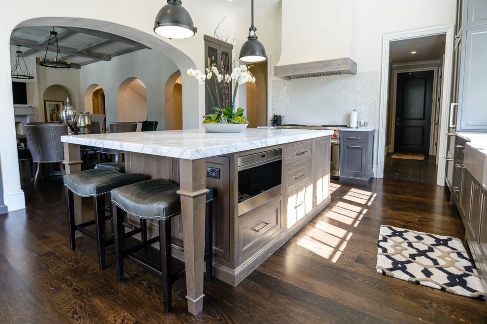 Example of a transitional kitchen design in St Louis with a farmhouse sink, beige backsplash, stainless steel appliances and an island
