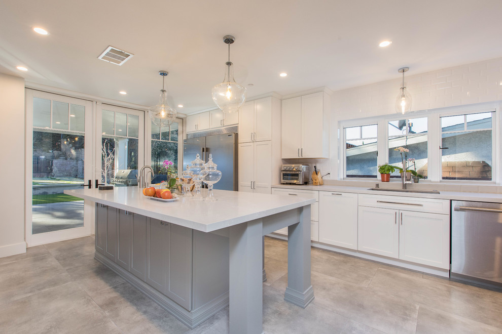 Mid-sized transitional single-wall porcelain tile and gray floor open concept kitchen photo in Los Angeles with an undermount sink, shaker cabinets, white cabinets, quartz countertops, white backsplash, subway tile backsplash, stainless steel appliances, an island and white countertops
