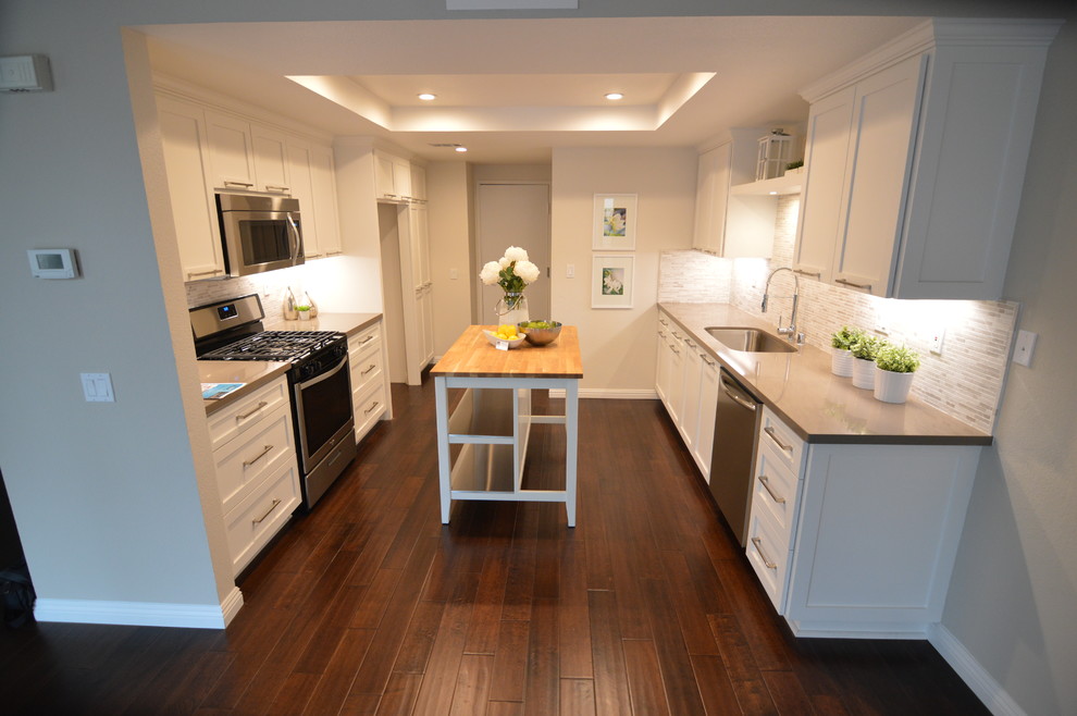 Inspiration for a mid-sized contemporary galley dark wood floor enclosed kitchen remodel in Los Angeles with an undermount sink, shaker cabinets, white cabinets, solid surface countertops, multicolored backsplash, subway tile backsplash, stainless steel appliances and an island