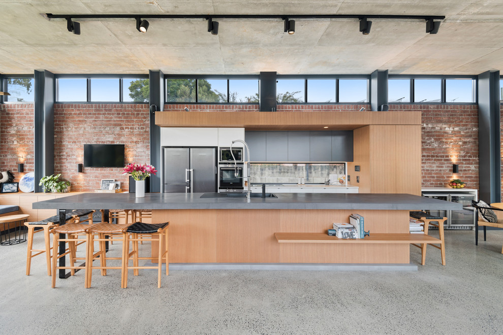 Immagine di una cucina industriale con lavello da incasso, ante lisce, ante in legno chiaro, paraspruzzi a finestra, pavimento in cemento, pavimento grigio e top grigio