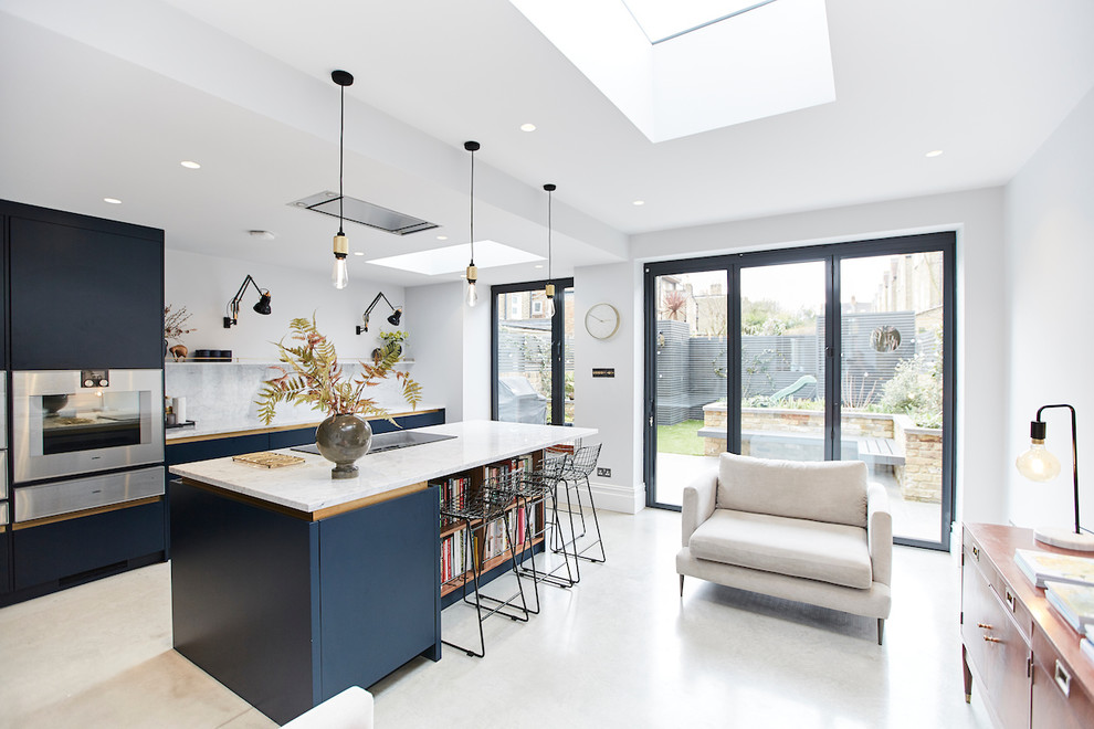 Inspiration for a mid-sized scandinavian concrete floor open concept kitchen remodel in London with flat-panel cabinets, blue cabinets, marble countertops, white backsplash, marble backsplash, stainless steel appliances, an island and white countertops