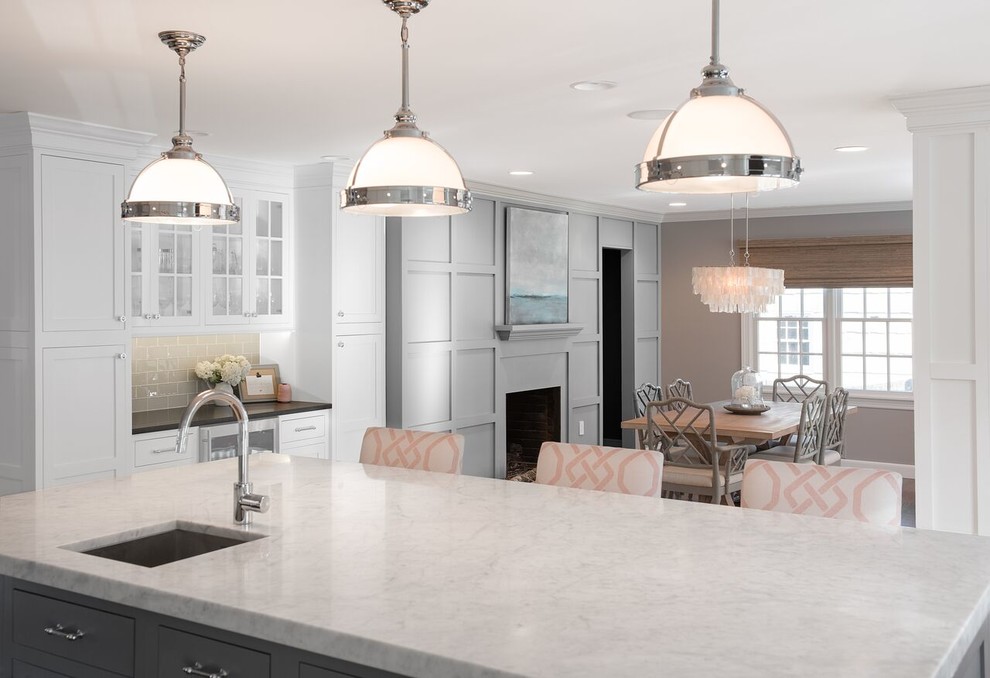 Mid-sized transitional u-shaped dark wood floor open concept kitchen photo in New York with a farmhouse sink, shaker cabinets, white cabinets, marble countertops, gray backsplash, glass tile backsplash, stainless steel appliances and an island