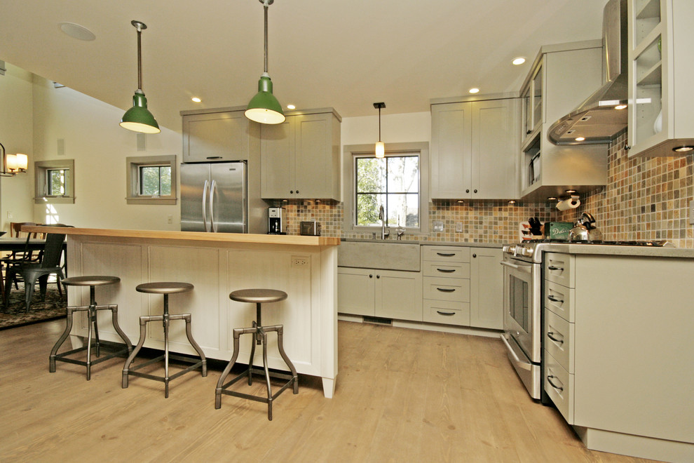 Exempel på ett modernt kök, med en rustik diskho, skåp i shakerstil, beige skåp, bänkskiva i betong, beige stänkskydd, stänkskydd i mosaik, rostfria vitvaror, ljust trägolv och en köksö