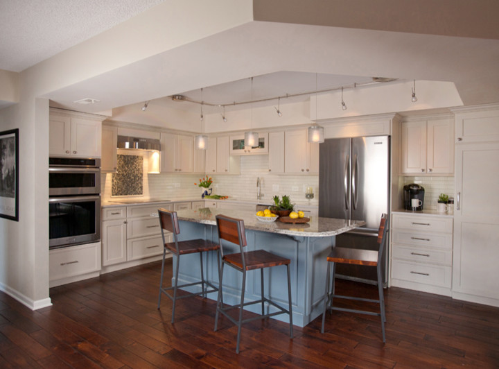 Inspiration for a mid-sized transitional l-shaped dark wood floor eat-in kitchen remodel in Chicago with an undermount sink, recessed-panel cabinets, white cabinets, quartz countertops, white backsplash, subway tile backsplash, stainless steel appliances and an island