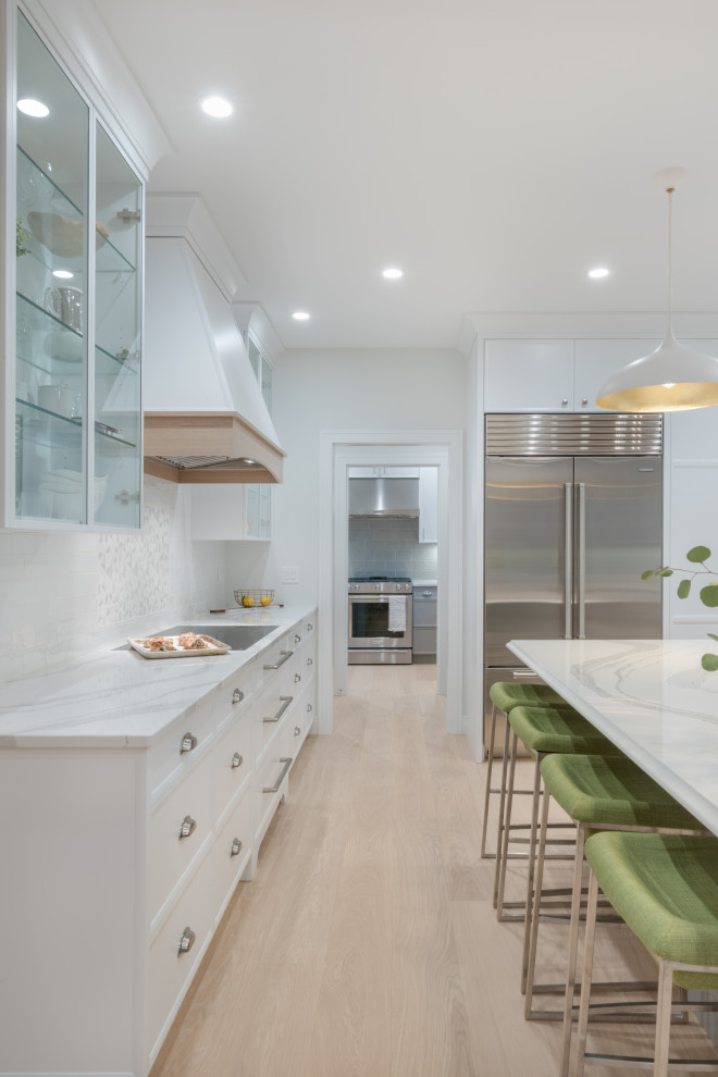 Foto på ett stort funkis vit kök och matrum, med släta luckor, vita skåp, bänkskiva i kvarts, vitt stänkskydd och en köksö